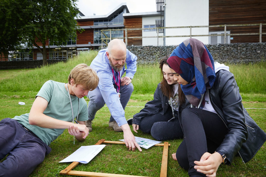 photo of students and teacher outside on the grass taking samples