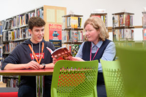 a picture of a student and a staff member reading a book together
