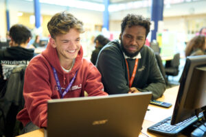 a picture of two students working together on a laptop