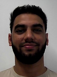 Man with short dark hair and beard, smiling slightly, against a plain white background.