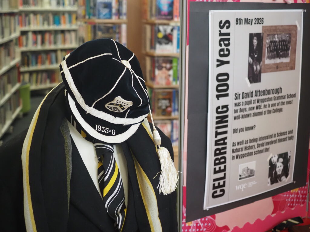 A mannequin in vintage school uniform stands next to a display celebrating 100 years of a grammar school.