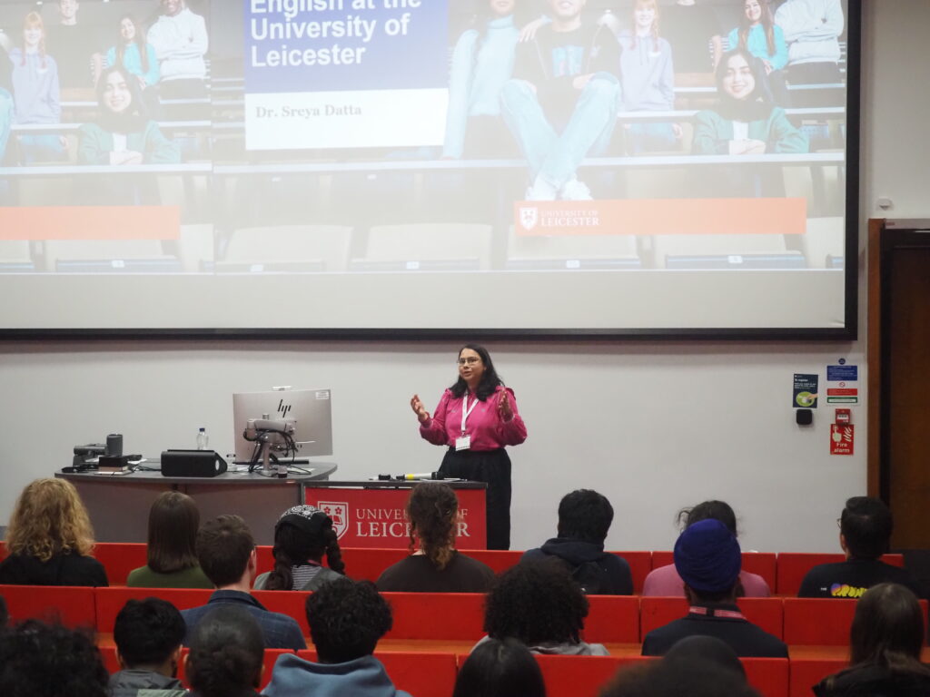 A woman speaks at a lectern to students in a lecture theatre at the University of Leicester.