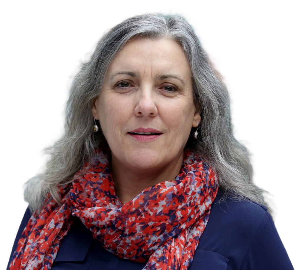 Woman with grey hair, a blue shirt, and a red patterned scarf, looking at the camera, on a white background.
